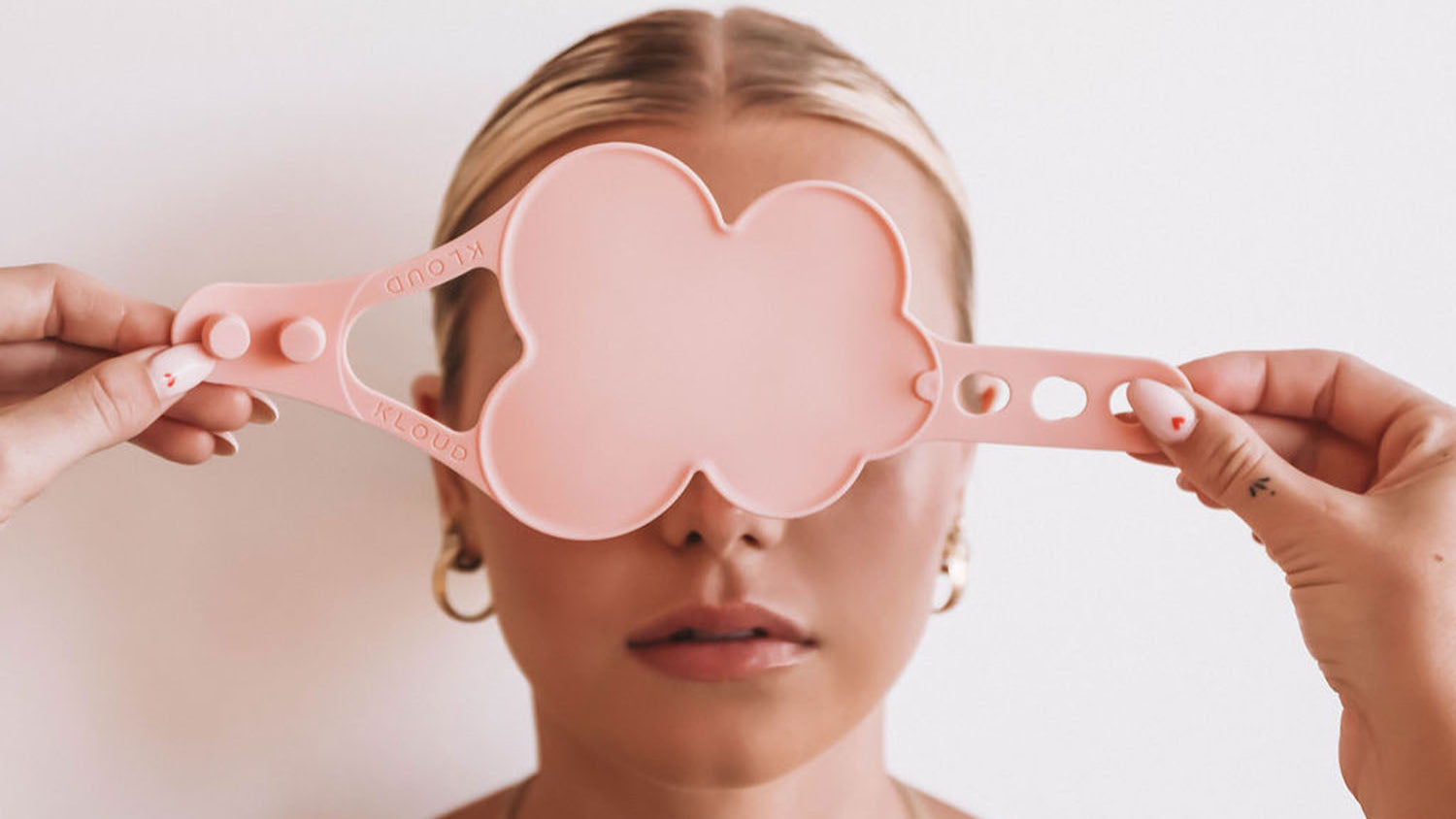 Beauty model holding a pastel pink Kloud Palette over her eyes, showcasing the cloud-shaped, latex-free hand palette designed for hygienic and mess-free mixing of cosmetics. Ideal for beauty professionals seeking innovative, allergy-conscious tools that enhance workflow and artistry.